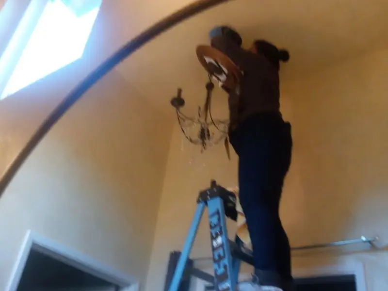 Electrician installing a chandelier in a Sanger residence